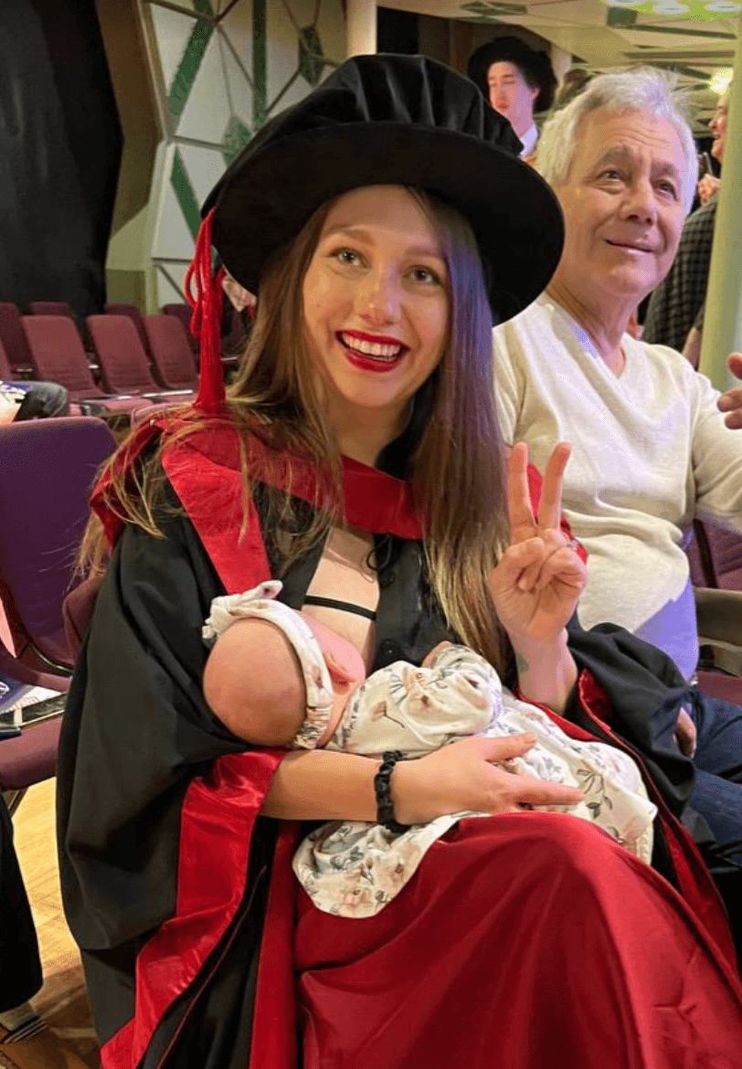 Dr. Val, founder of Snorri, in her graduation gown holding her baby.